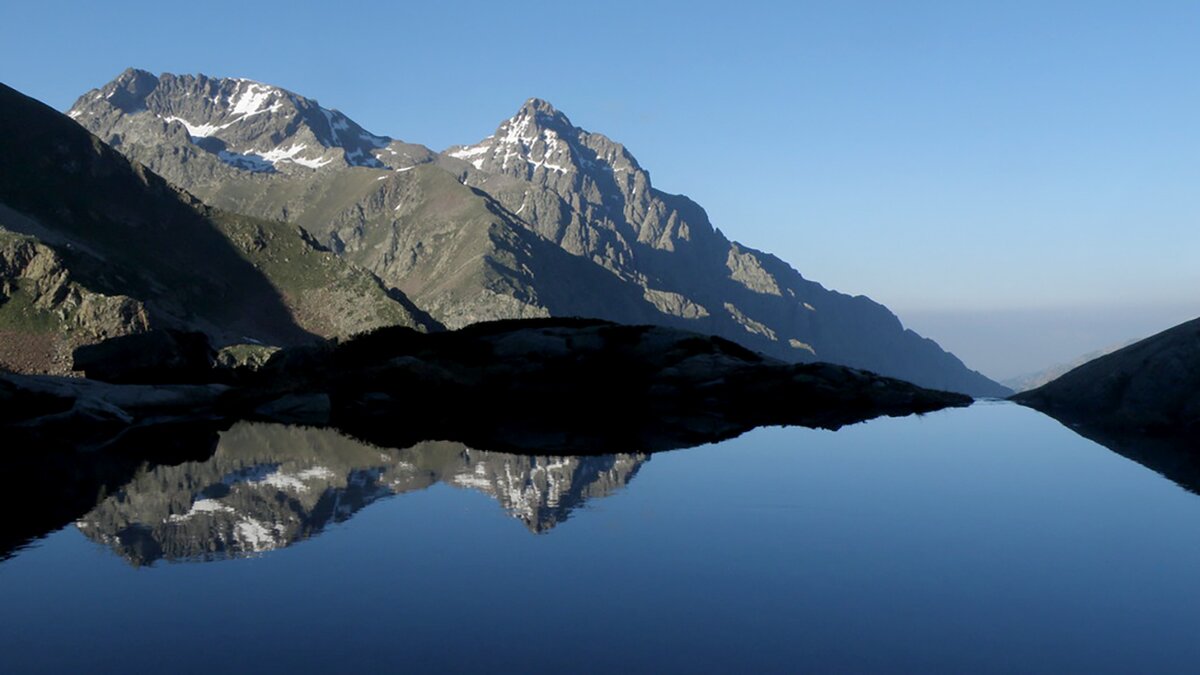 Il Lago del Claus nelle Alpi Marittime, con le montagne circostanti riflesse nelle acque del lago sotto un cielo terso. Archivio APAM. Fine descrizione dell’immagine.